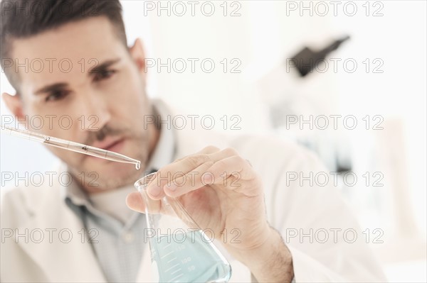 Man pouring liquid into conical flask.