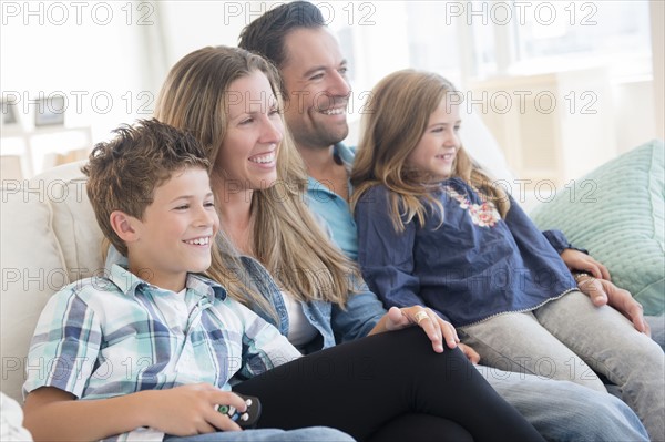 Family with two children (6-7, 8-9) sitting on sofa