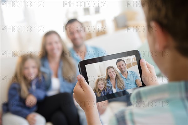 Boy (8-9) photographing family with digital tablet