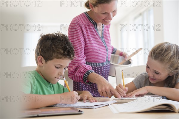 Mother assisting children (6-7, 8-9) with homework
