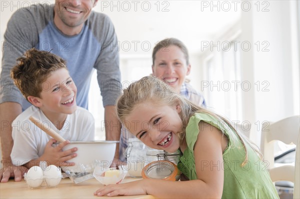 Family with two children (6-7, 8-9) preparing food, laughing