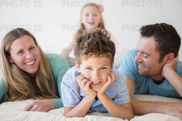 Family with two children (6-7, 8-9) lying in bed
