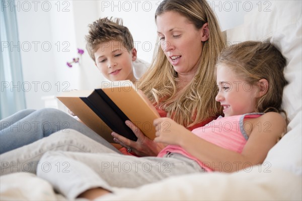 Mother reading with daughter (6-7) and son (8-9)