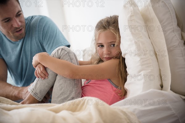 Father talking to daughter (6-7) in bedroom