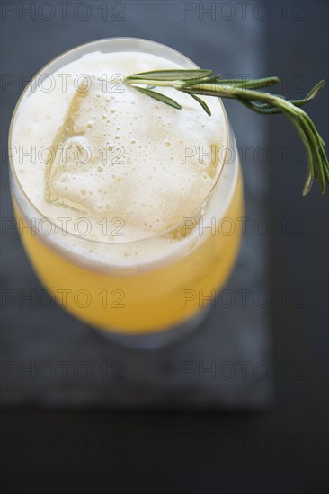 Cocktail in wine glass with twig of rosemary