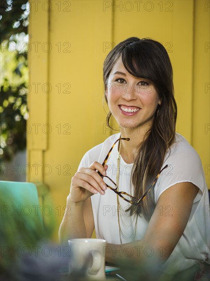 Young woman holding eyeglasses and looking at camera