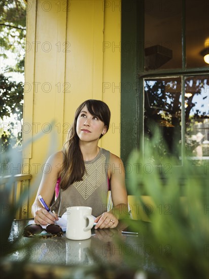 Young woman sitting on porch looking up