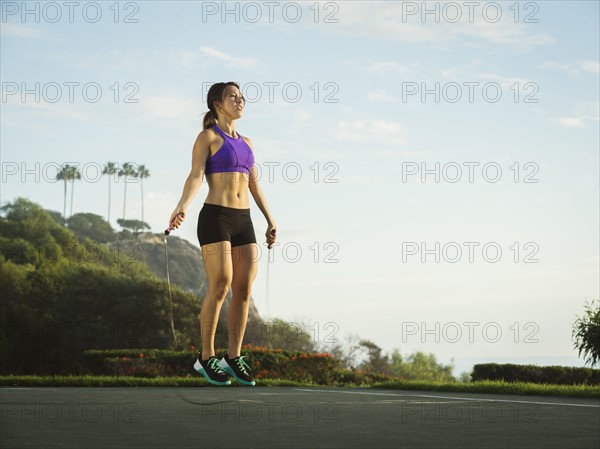 Young woman jumping rope in park