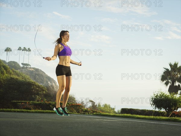 Young woman jumping rope in park