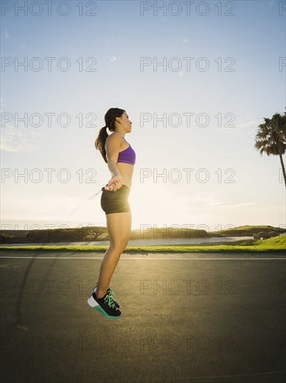 Young woman jumping rope in park