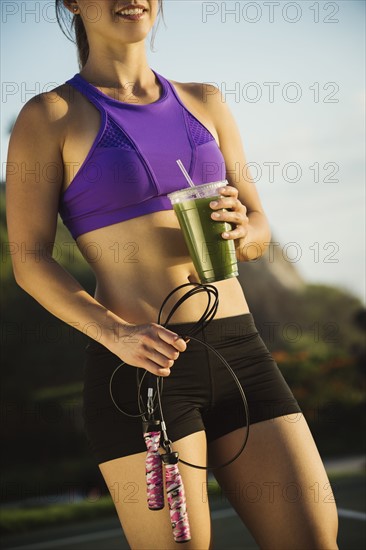 Young woman holding jump rope and smoothie