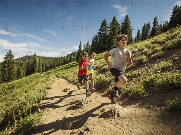 Three children (10-11, 12-13, 14-15) running in mountains