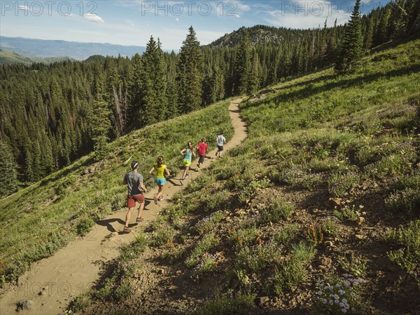 Family with three children (10-11, 12-13, 14-15) running in mountains