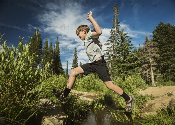 Boy (12-13) jumping in forest