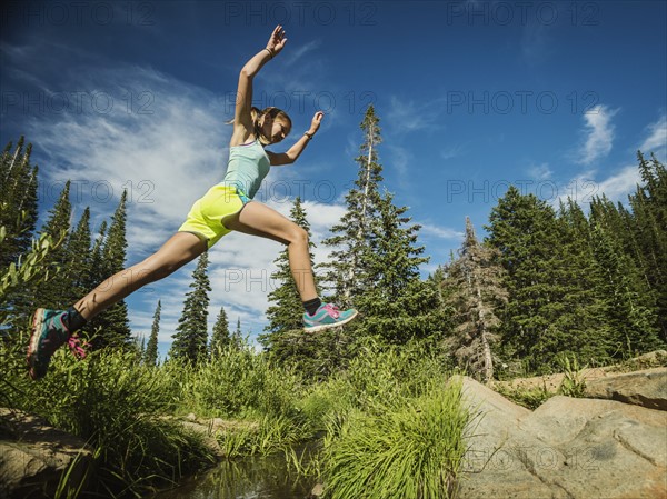 Teenage girl (14-15) jumping in forest