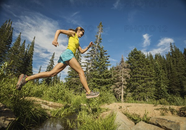 Mature woman jumping over stream