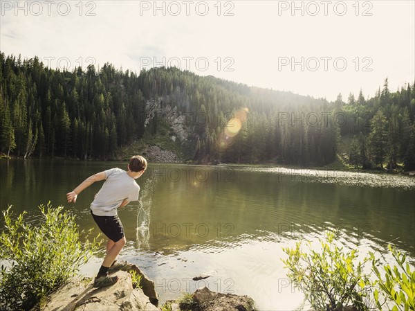 Boy (12-13) throwing stone into lake