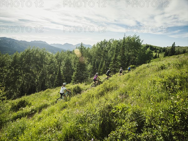 Family with children (10-11, 12-13, 14-15) cycling in mountains