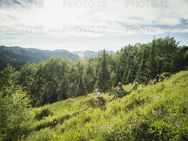 Family with children (10-11, 12-13, 14-15) cycling in mountains