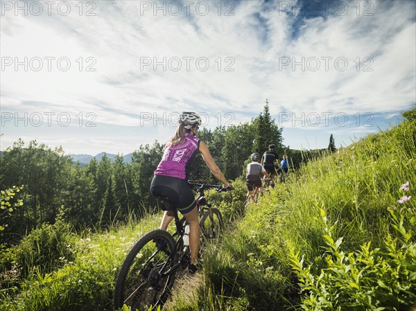 Family with children ( 10-11, 12-13) cycling in mountains