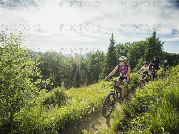 Family with children ( 10-11, 12-13) cycling in mountains