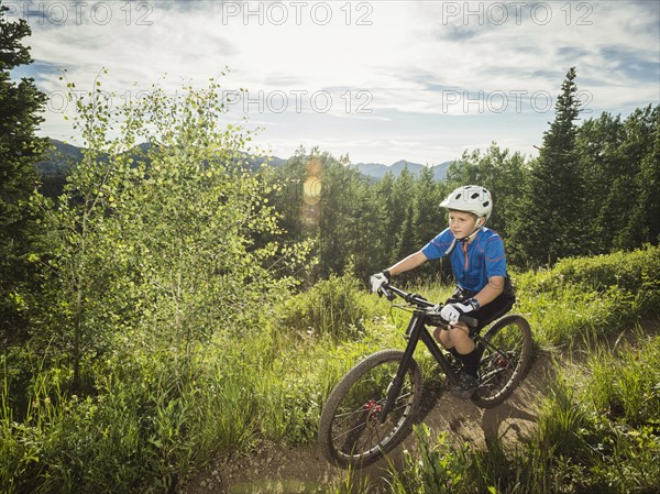 Boy (10-11) cycling in mountains