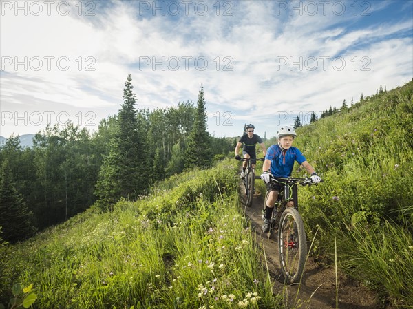 Father and son (10-11) cycling in mountains