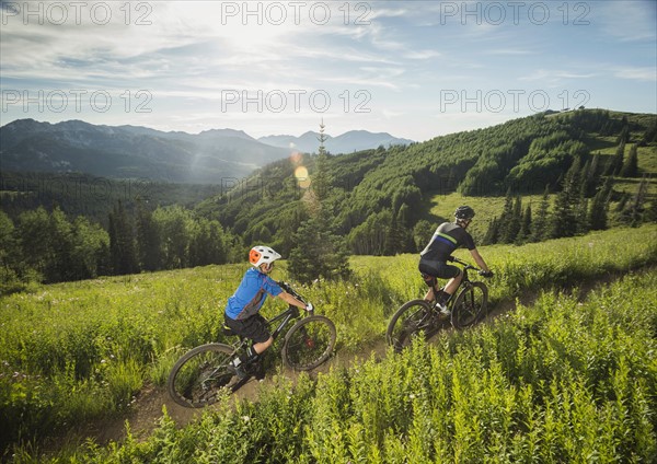 Father and son (10-11) cycling in mountains