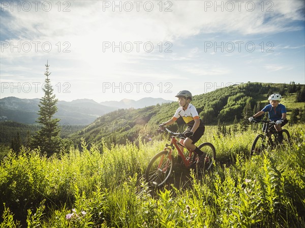 Boys (10-11, 12-13) during bicycle trip in mountain scenery