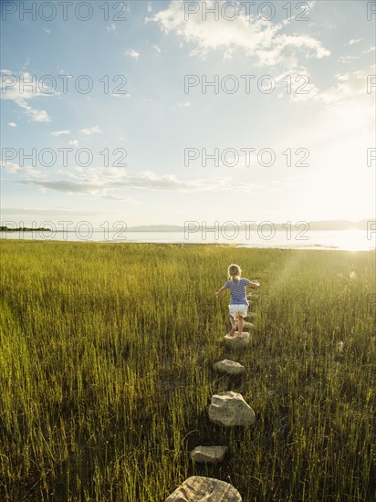 Small girl (4-5) walking on stepping stones in meadow