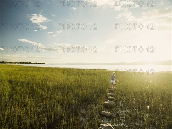 Small girl (4-5) walking on stepping stones in meadow