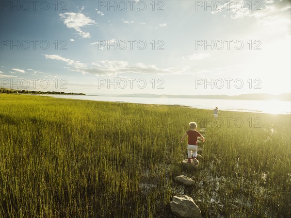 Small girl and boy (4-5) walking on stepping stones in meadow