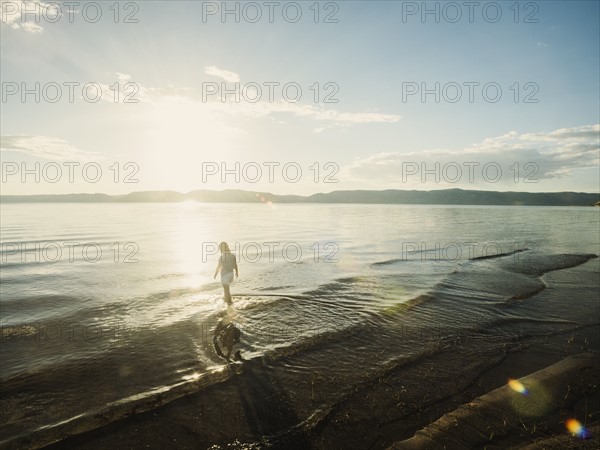 Small girl (4-5) wading in lake on sunny day