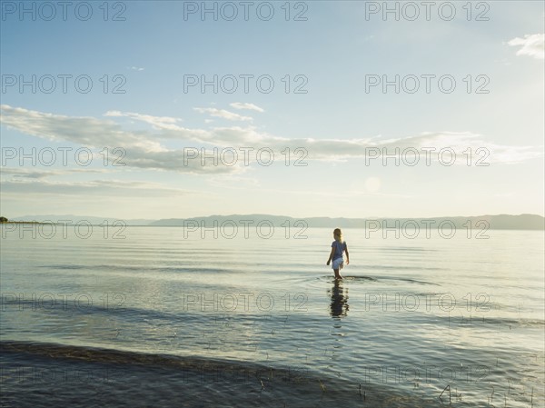 Small girl (4-5) wading in lake on sunny day