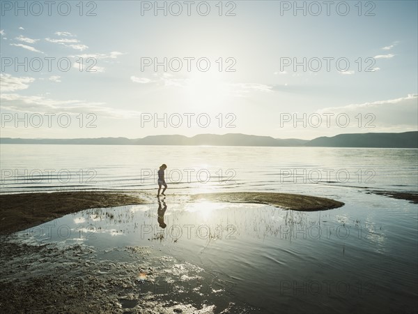 Small girl (4-5) wading in lake on sunny day
