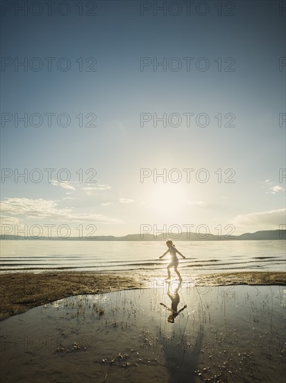 Small girl (4-5) wading in lake on sunny day