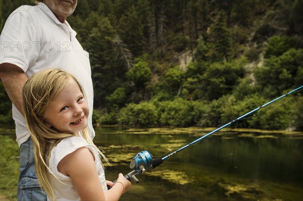 Small girl (4-5) fishing with grandfather