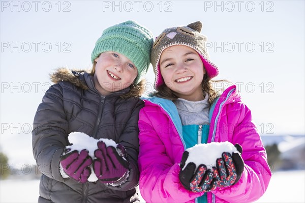 Portrait of girls (8-9, 10-11) holding snow