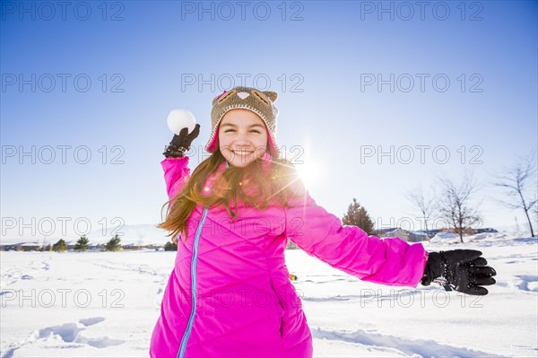 Girl (10-11) in pink jacket throwing snowball