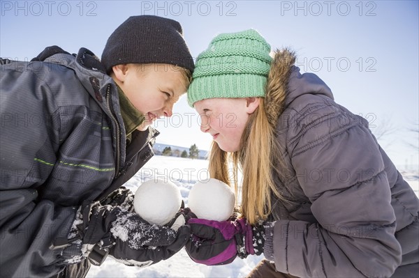 Children (8-9, 10-11) holding snowballs and touching foreheads