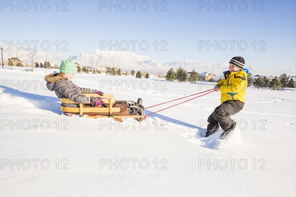 Children (8-9) playing with sled in snow