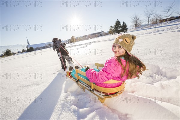 Children (8-9, 10-11) playing with sled in snow