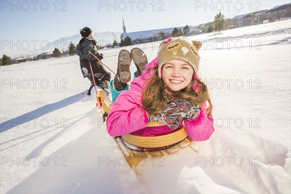 Children (8-9, 10-11) playing with sled in snow