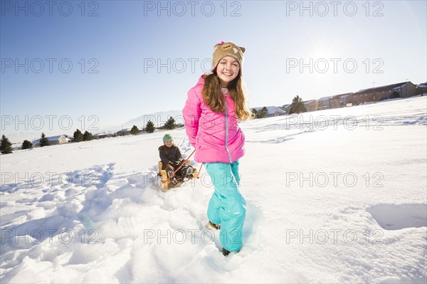 Children (8-9, 10-11) playing with sled in snow