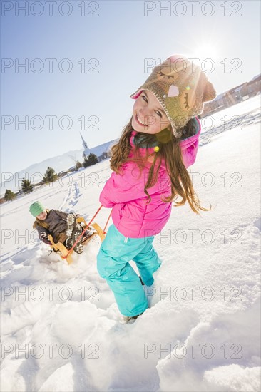 Children (8-9, 10-11) playing with sled