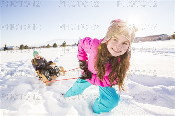 Children (8-9, 10-11) playing with sled in snow