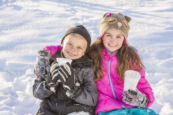 Boy (8-9) and girl (10-11) warming up drinking hot chocolate