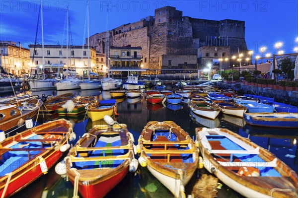 Colorful boats and Castel dell' Ovo at night