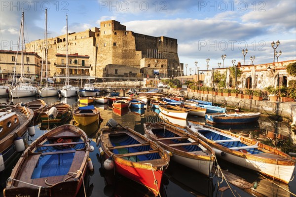 Colorful boats and Castel dell' Ovo at night