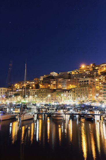 Boats in city marina at night